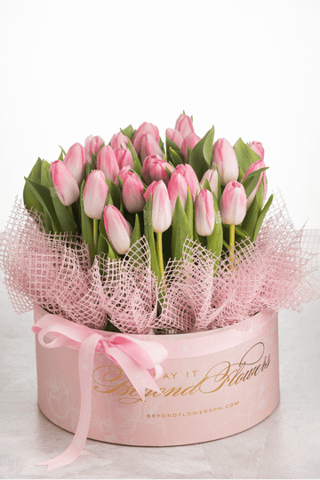 A bouquet of pink tulips in a pink surprise cylinder