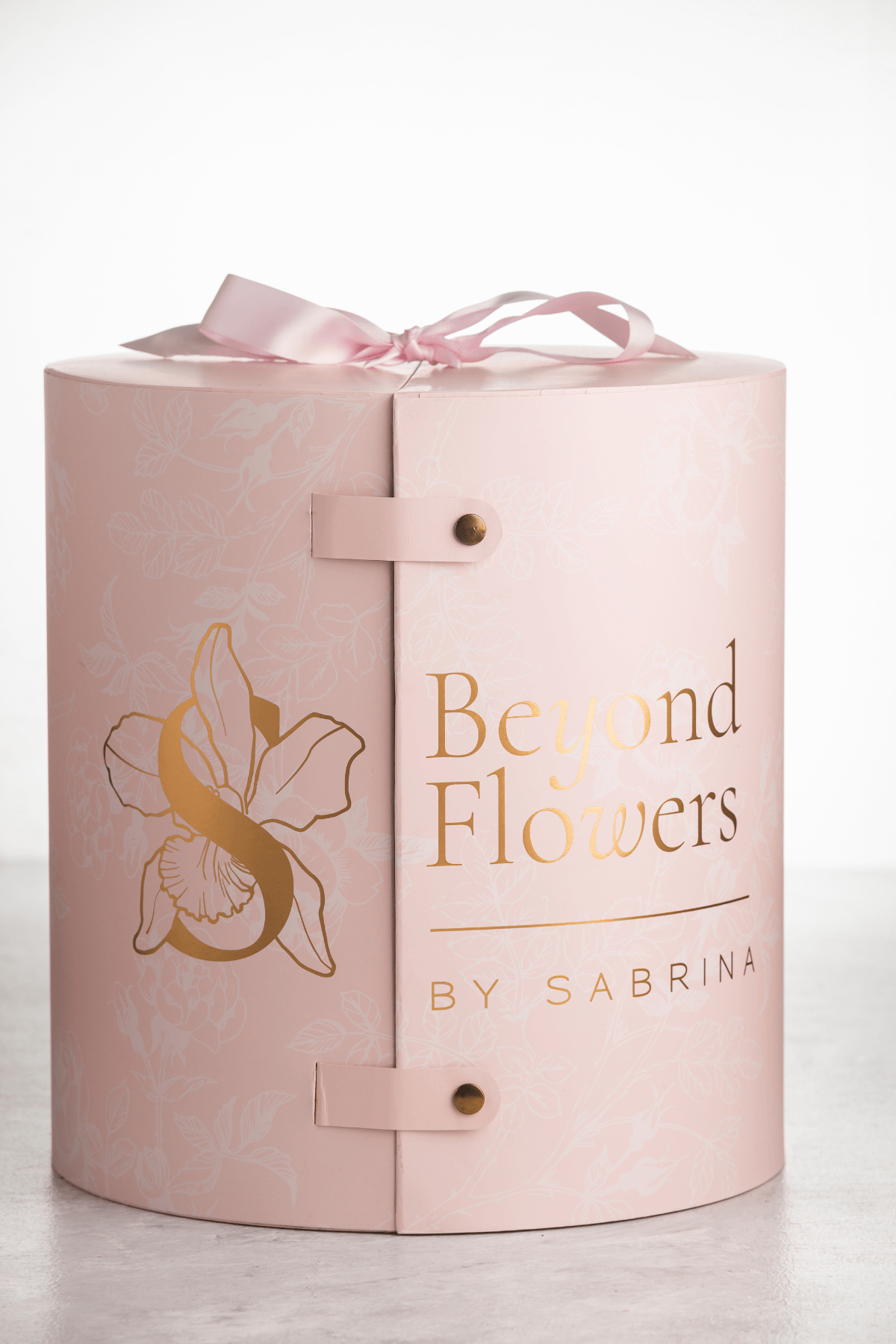 A pink cylinder for flowers with gold stamp of Beyond Flowers by Sabrina